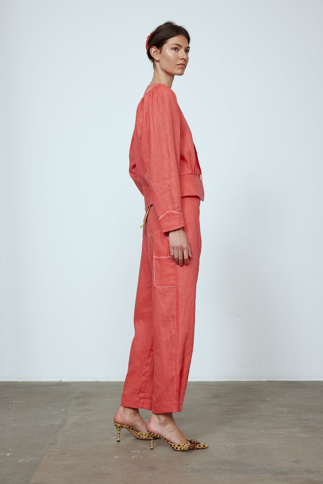 The Emma Pants in Orange Linen. The pants feature cargo details on the side and large pockets with piping details in a contrasting color. Easily modify the shape of the pants with a button adjustment. Style them with a t-shirt, blouse, or a matching Emma Jacket in Orange Linen. Also available in Pink and Navy.