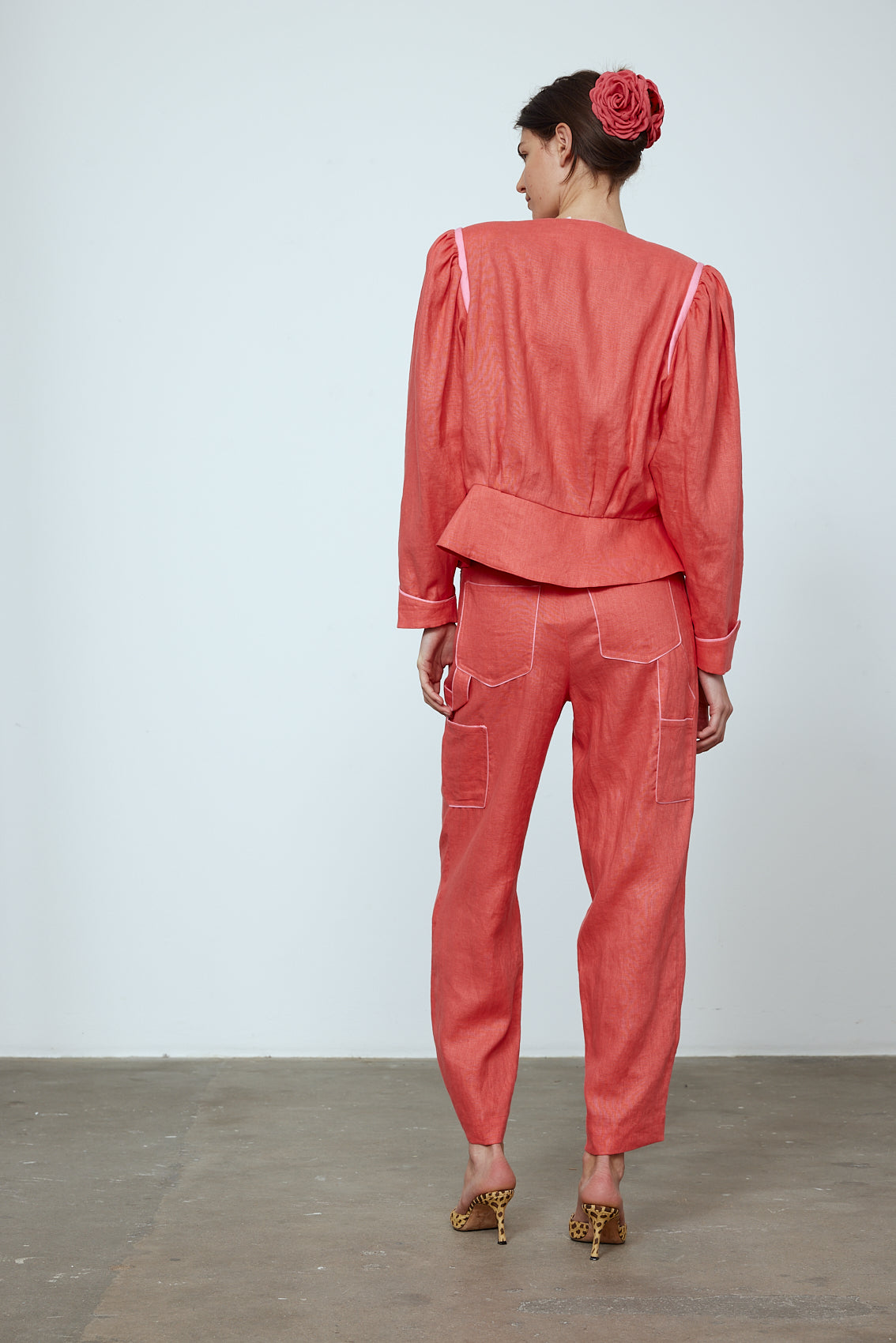 The Emma Pants in Orange Linen. The pants feature cargo details on the side and large pockets with piping details in a contrasting color. Easily modify the shape of the pants with a button adjustment. Style them with a t-shirt, blouse, or a matching Emma Jacket in Orange Linen. Also available in Pink and Navy.