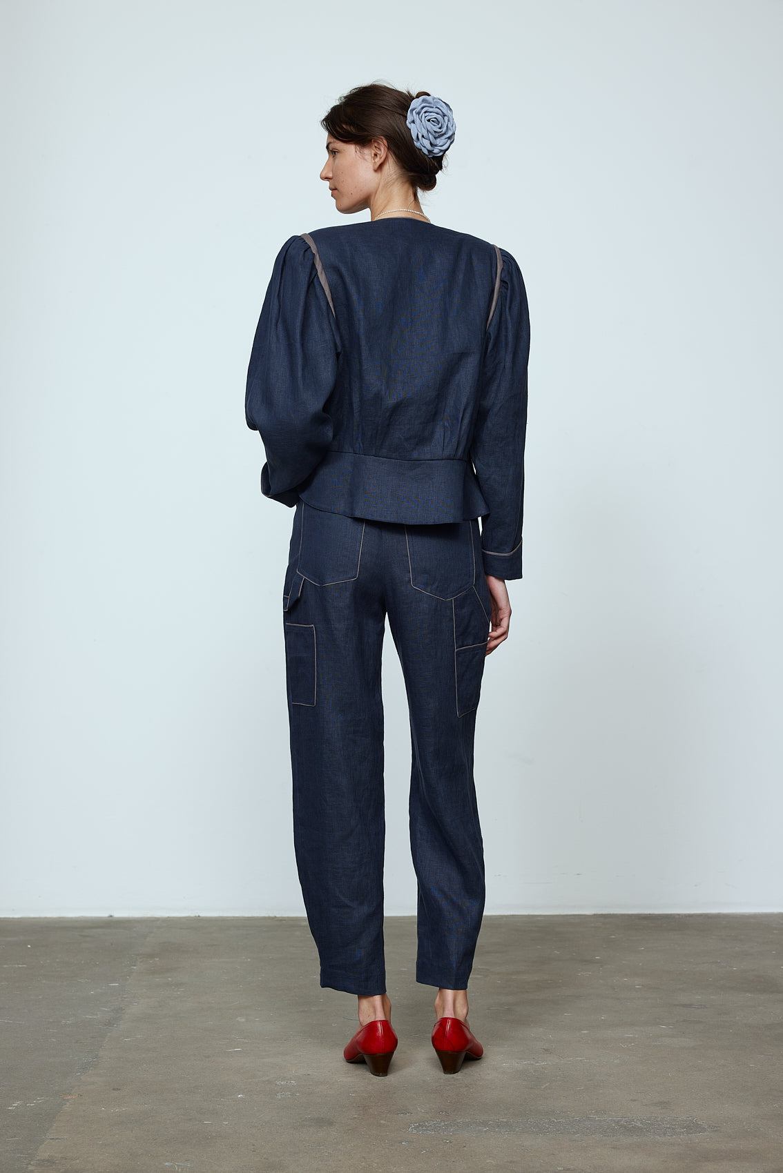 The Emma Pants in Navy Linen. The pants feature cargo details on the side and large pockets with piping details in a contrasting color. Easily modify the shape of the pants with a button adjustment. Style them with a t-shirt, blouse, or a matching Emma Jacket in Navy Linen. Also available in Pink and Orange. Material: 100% linen. Lining: 100% viscose.