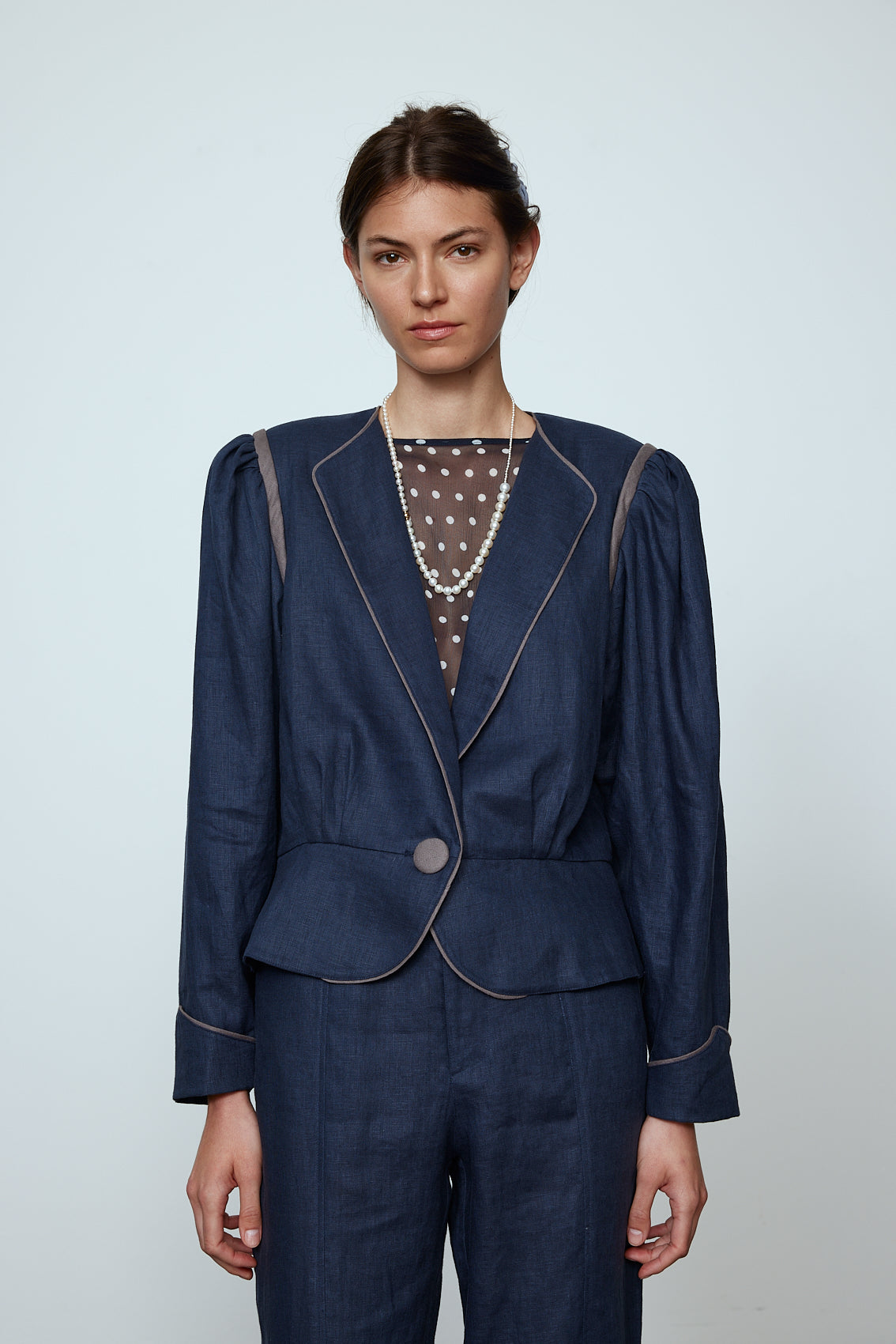 The Emma Jacket in Navy Linen. A new flattering jacket shape inspired by Caroline's favorite vintage 70's finds. The Jacket features a single-button closing, balloon sleeves, and contrasting color piping details around the edges. Also available in Pink/Green and Orange/Pink.