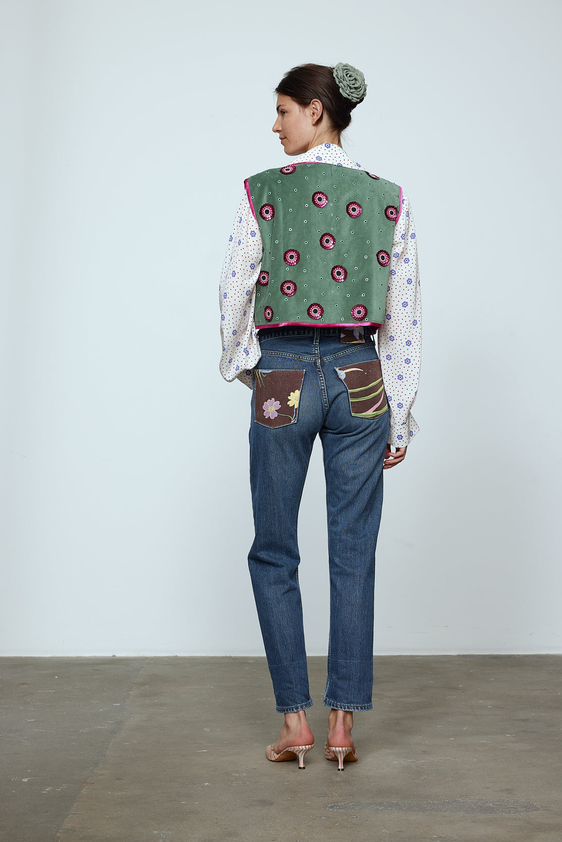 The Ravnbak Vest in Olive Green velvet with a pink lining. The vest is exquisitely hand-embroidered by skilled artisans in our flower daisy pattern using beadings and sequins. Style it over a shirt, dress, or top. Also available in Baby Pink.