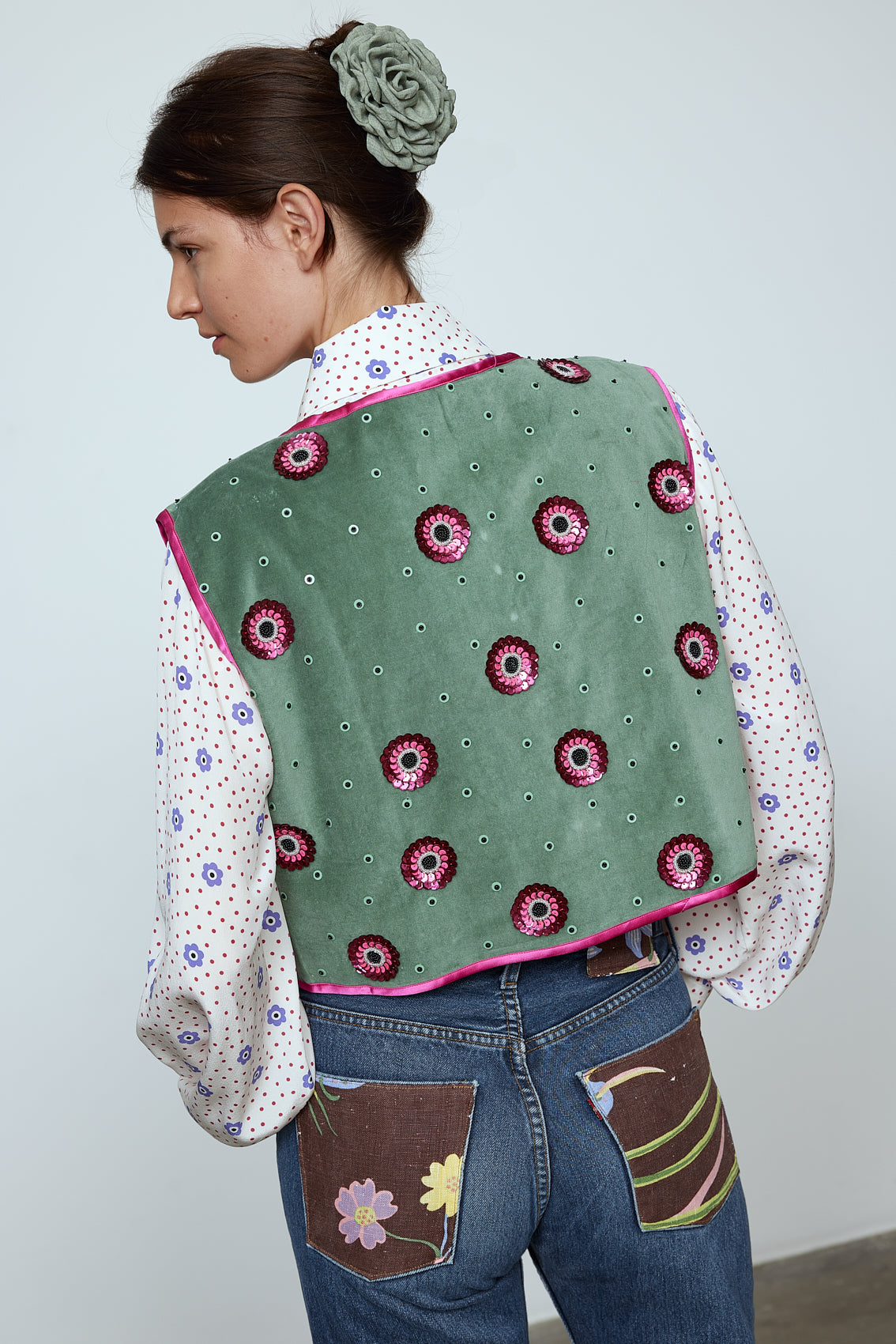 The Ravnbak Vest in Olive Green velvet with a pink lining. The vest is exquisitely hand-embroidered by skilled artisans in our flower daisy pattern using beadings and sequins. Style it over a shirt, dress, or top. Also available in Baby Pink.