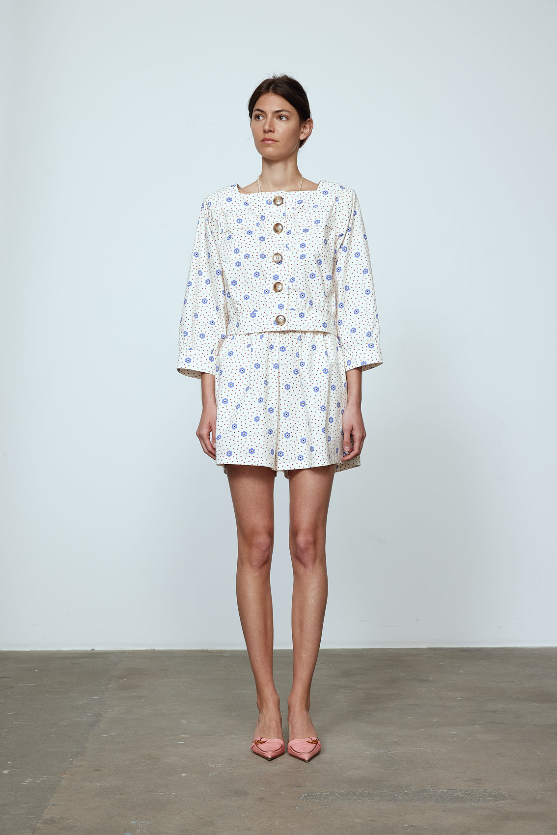 The Aggi Shirt is a new style inspired by Caroline's favorite shapes of the 70s. It features a square-cut neckline, three-quarter-length sleeves, pockets, big contrasting buttons, and a waistband. Material: 100% cotton. The model is 179cm (5'10") and wears size S.