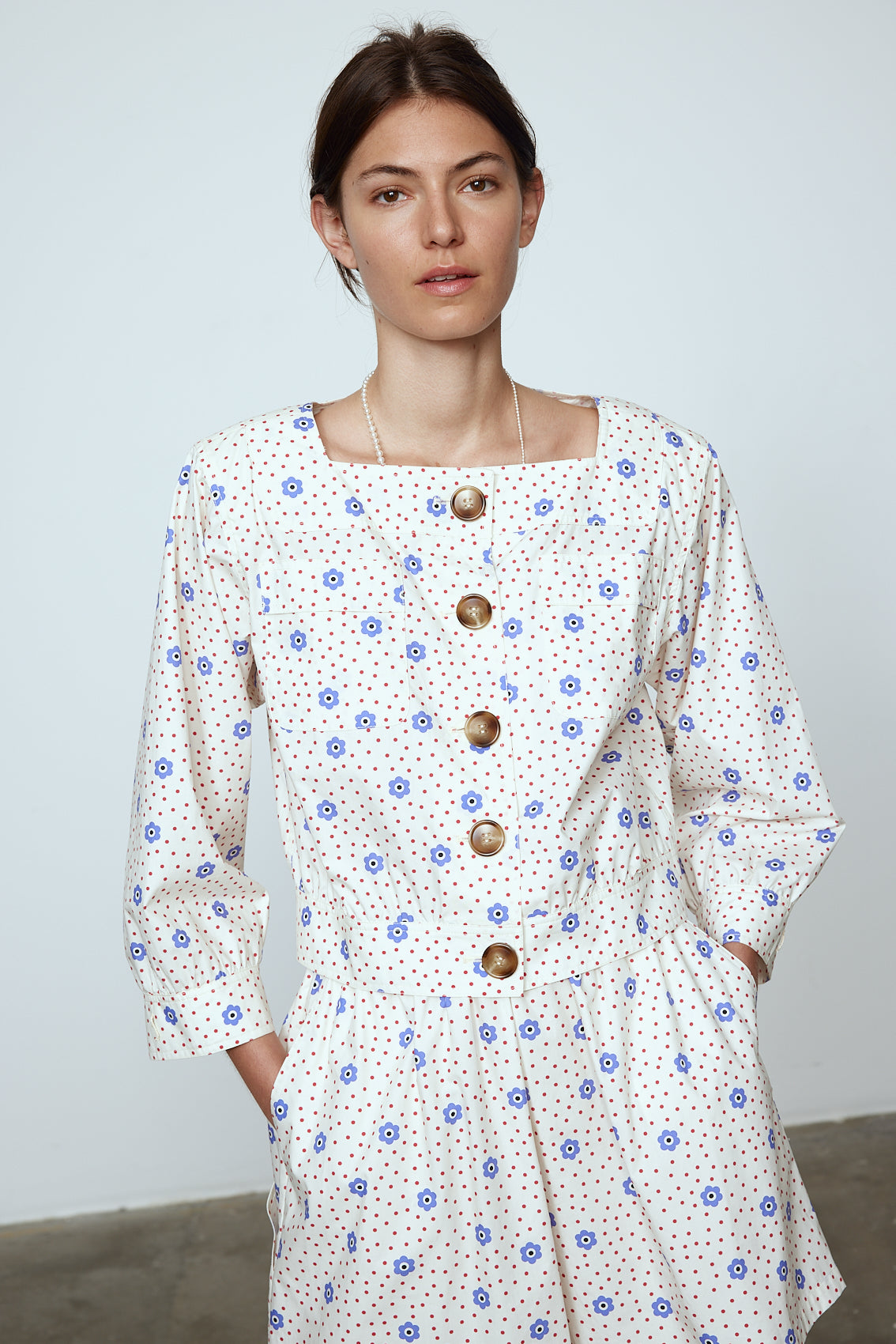 The Aggi Shirt is a new style inspired by Caroline's favorite shapes of the 70s. It features a square-cut neckline, three-quarter-length sleeves, pockets, big contrasting buttons, and a waistband. Material: 100% cotton. The model is 179cm (5'10") and wears size S.