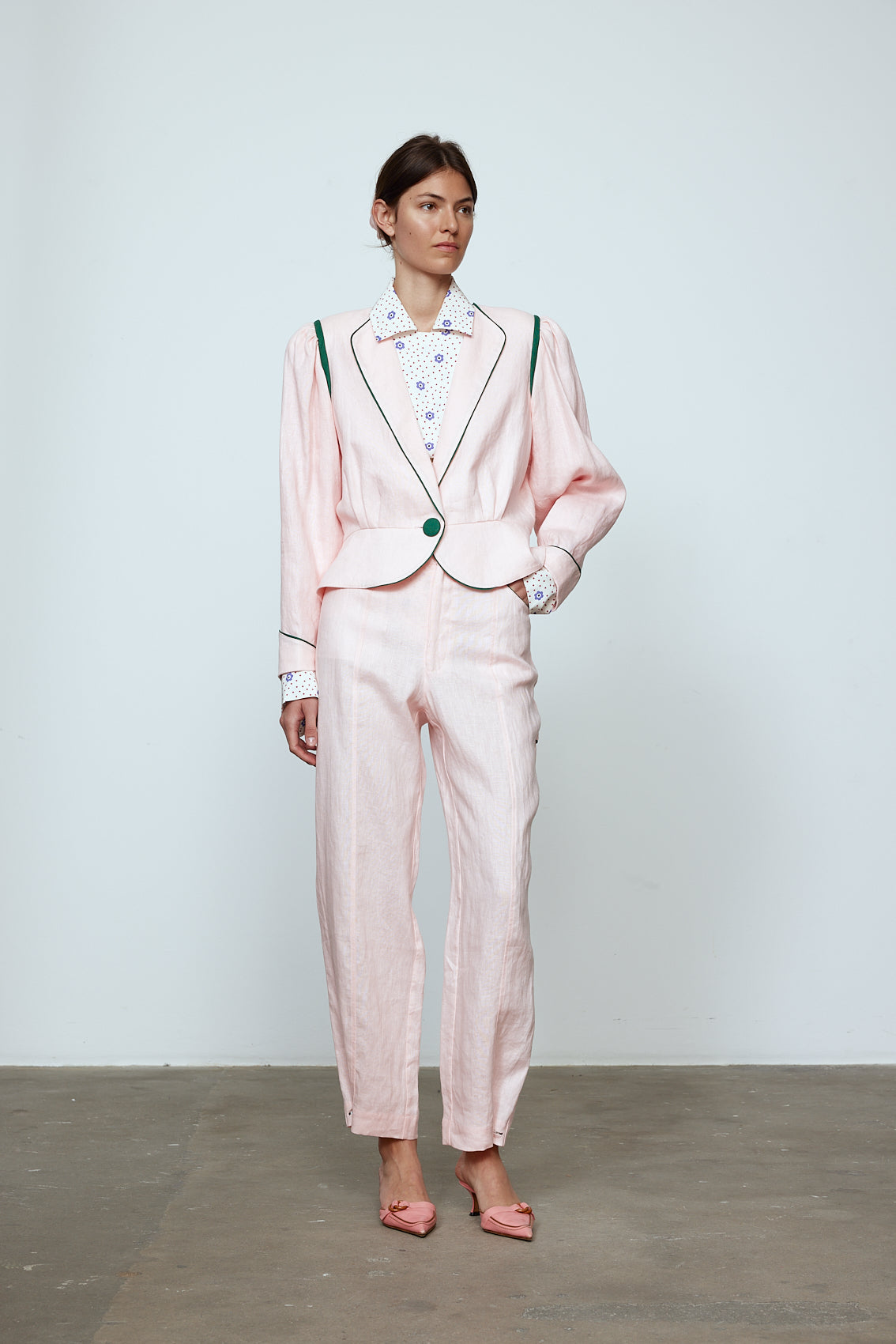 The Emma Pants in Baby Pink Linen. The pants feature cargo details on the side and large pockets with piping details in a contrasting color. Easily modify the shape of the pants with a button adjustment. Style them with a t-shirt, blouse, or a matching Emma Jacket in Baby Pink Linen. Also available in Orange and Navy.