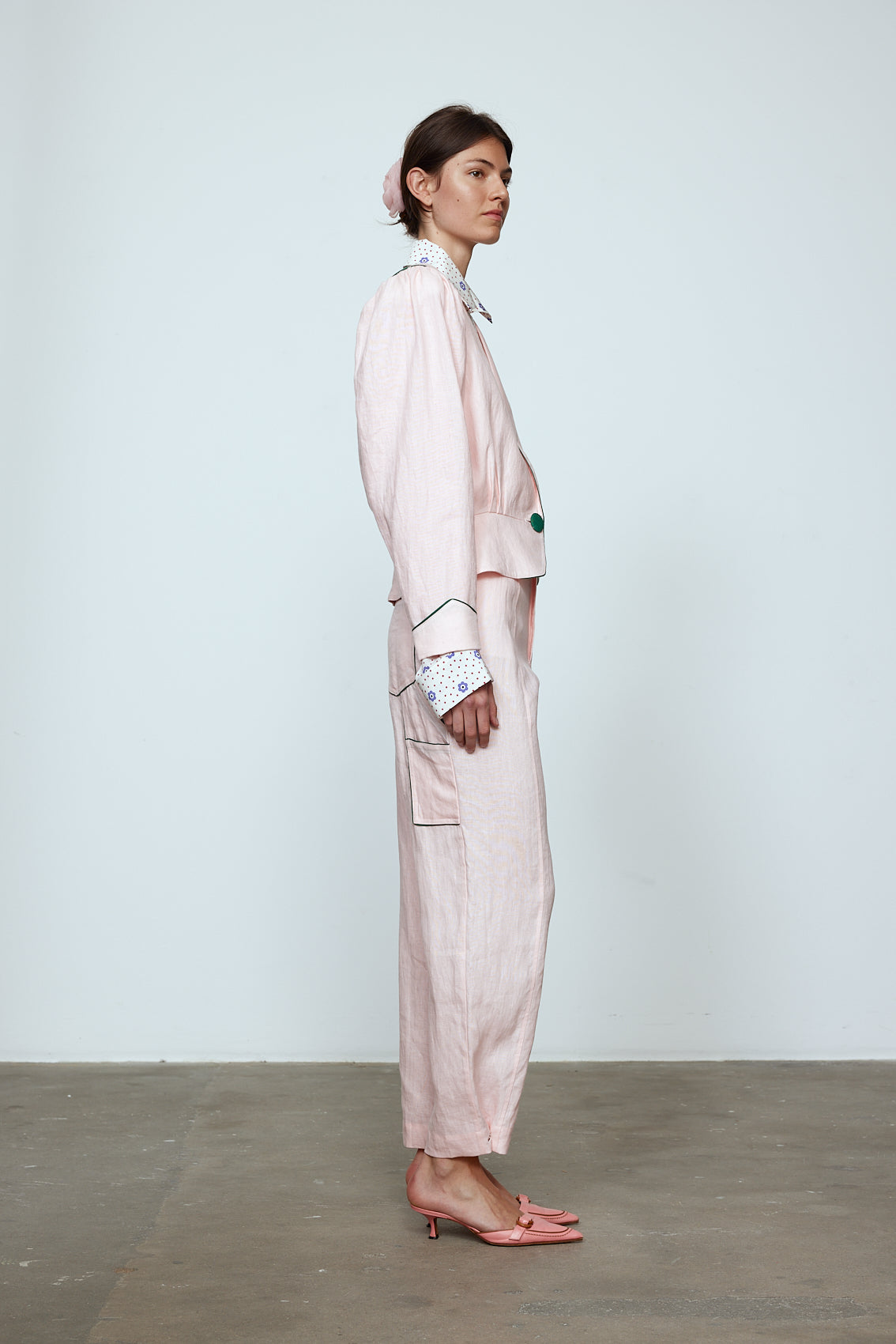 The Emma Pants in Baby Pink Linen. The pants feature cargo details on the side and large pockets with piping details in a contrasting color. Easily modify the shape of the pants with a button adjustment. Style them with a t-shirt, blouse, or a matching Emma Jacket in Baby Pink Linen. Also available in Orange and Navy.