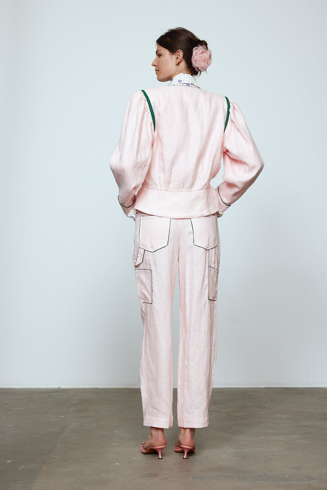 The Emma Pants in Baby Pink Linen. The pants feature cargo details on the side and large pockets with piping details in a contrasting color. Easily modify the shape of the pants with a button adjustment. Style them with a t-shirt, blouse, or a matching Emma Jacket in Baby Pink Linen. Also available in Orange and Navy.