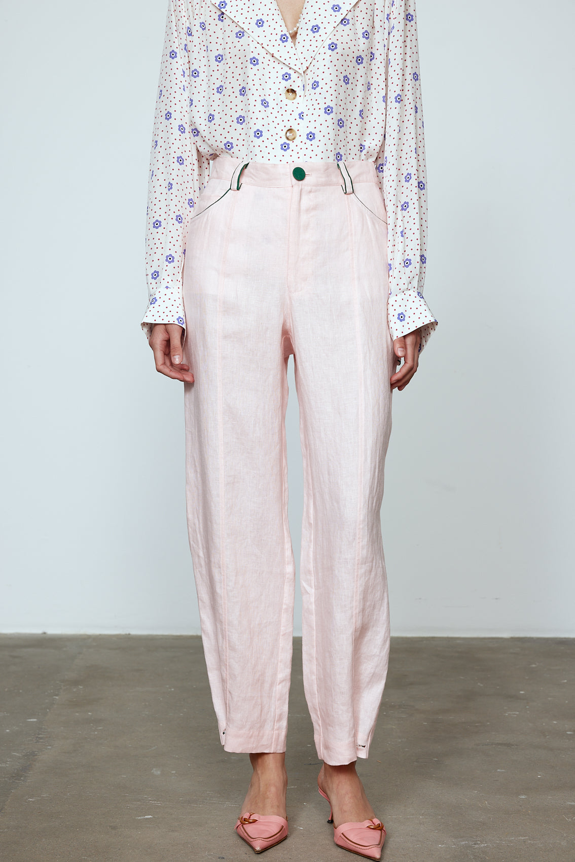 The Emma Pants in Baby Pink Linen. The pants feature cargo details on the side and large pockets with piping details in a contrasting color. Easily modify the shape of the pants with a button adjustment. Style them with a t-shirt, blouse, or a matching Emma Jacket in Baby Pink Linen. Also available in Orange and Navy.