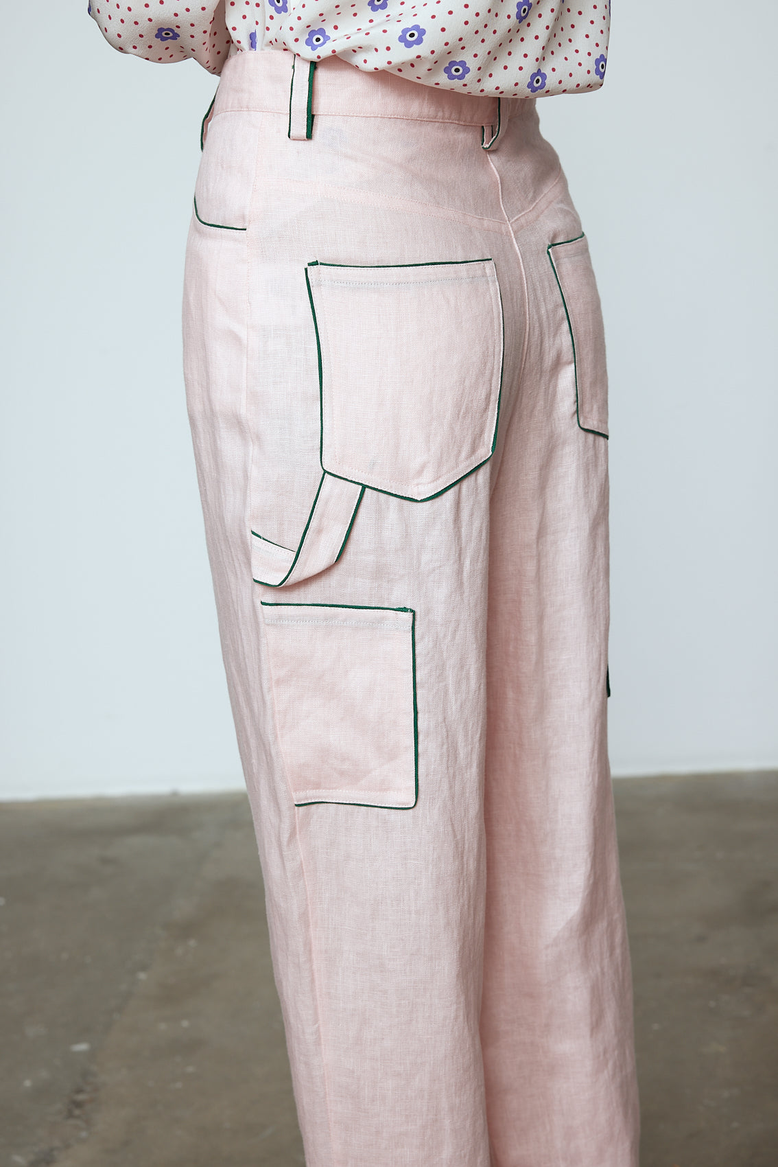 The Emma Pants in Baby Pink Linen. The pants feature cargo details on the side and large pockets with piping details in a contrasting color. Easily modify the shape of the pants with a button adjustment. Style them with a t-shirt, blouse, or a matching Emma Jacket in Baby Pink Linen. Also available in Orange and Navy.