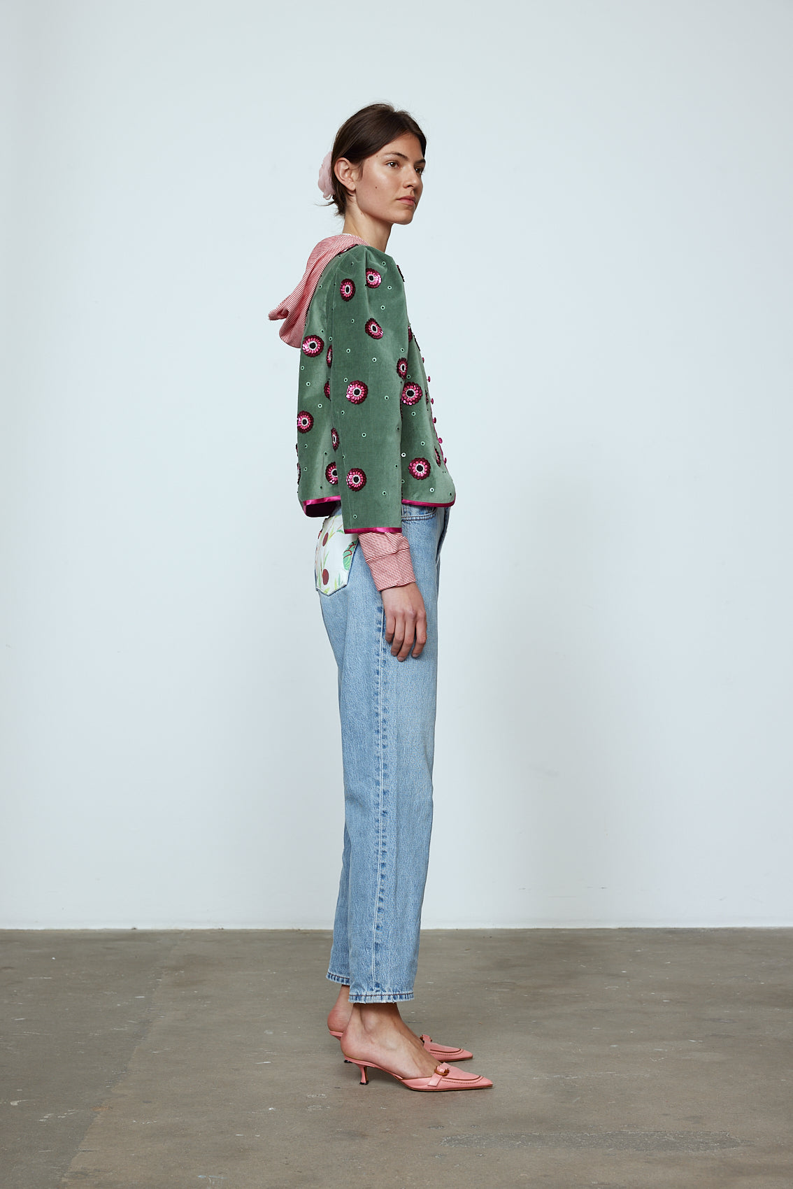 The Blanca Jacket in luxurious olive green silk velvet, exquisitely hand-embroidered by skilled artisans in our flower daisy pattern using beadings and sequins. The jacket features pink silk-button closings on the front and pink silk lining.