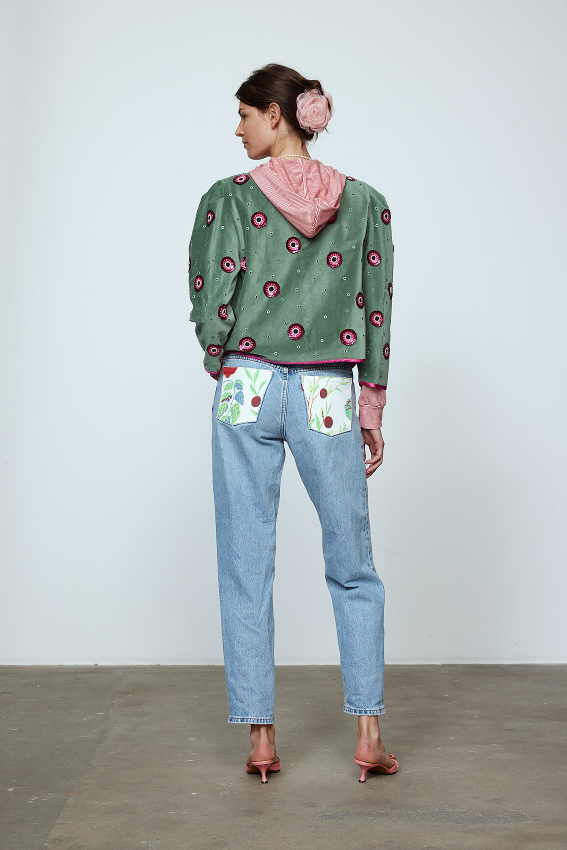 The Blanca Jacket in luxurious olive green silk velvet, exquisitely hand-embroidered by skilled artisans in our flower daisy pattern using beadings and sequins. The jacket features pink silk-button closings on the front and pink silk lining.