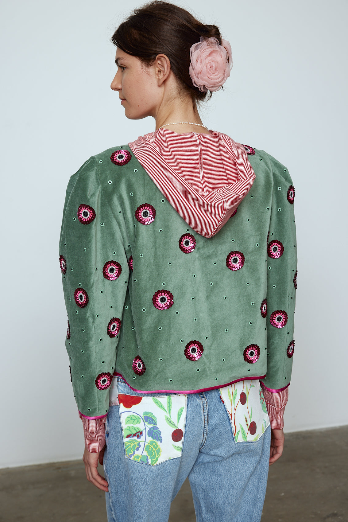 The Blanca Jacket in luxurious olive green silk velvet, exquisitely hand-embroidered by skilled artisans in our flower daisy pattern using beadings and sequins. The jacket features pink silk-button closings on the front and pink silk lining.
