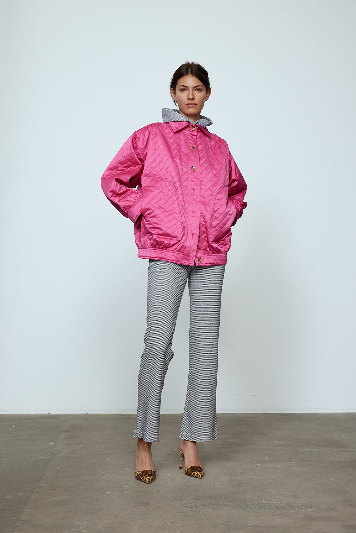 The Mimi Jacket in Hot Pink Duchess. A new rounded shape inspired by the 80s in shiny quilted fabric with orange lining and big round buttons. Style it over dresses, jeans, or leggings. Material: 100% polyester. Lining: 100 % viscose.