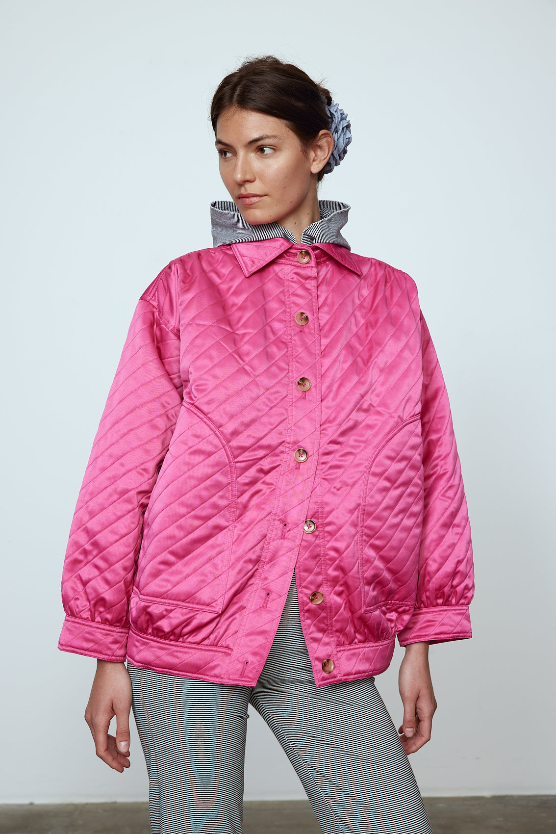 The Mimi Jacket in Hot Pink Duchess. A new rounded shape inspired by the 80s in shiny quilted fabric with orange lining and big round buttons. Style it over dresses, jeans, or leggings. Material: 100% polyester. Lining: 100 % viscose.