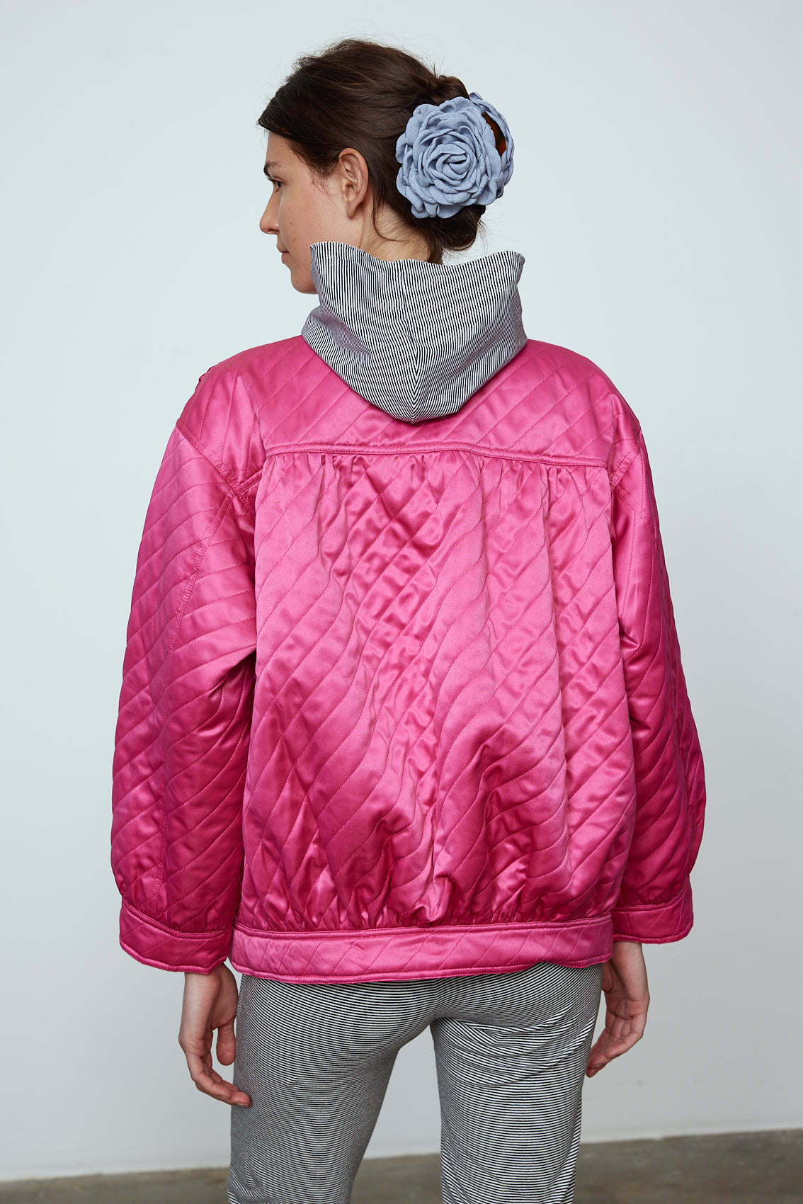 The Mimi Jacket in Hot Pink Duchess. A new rounded shape inspired by the 80s in shiny quilted fabric with orange lining and big round buttons. Style it over dresses, jeans, or leggings. Material: 100% polyester. Lining: 100 % viscose.