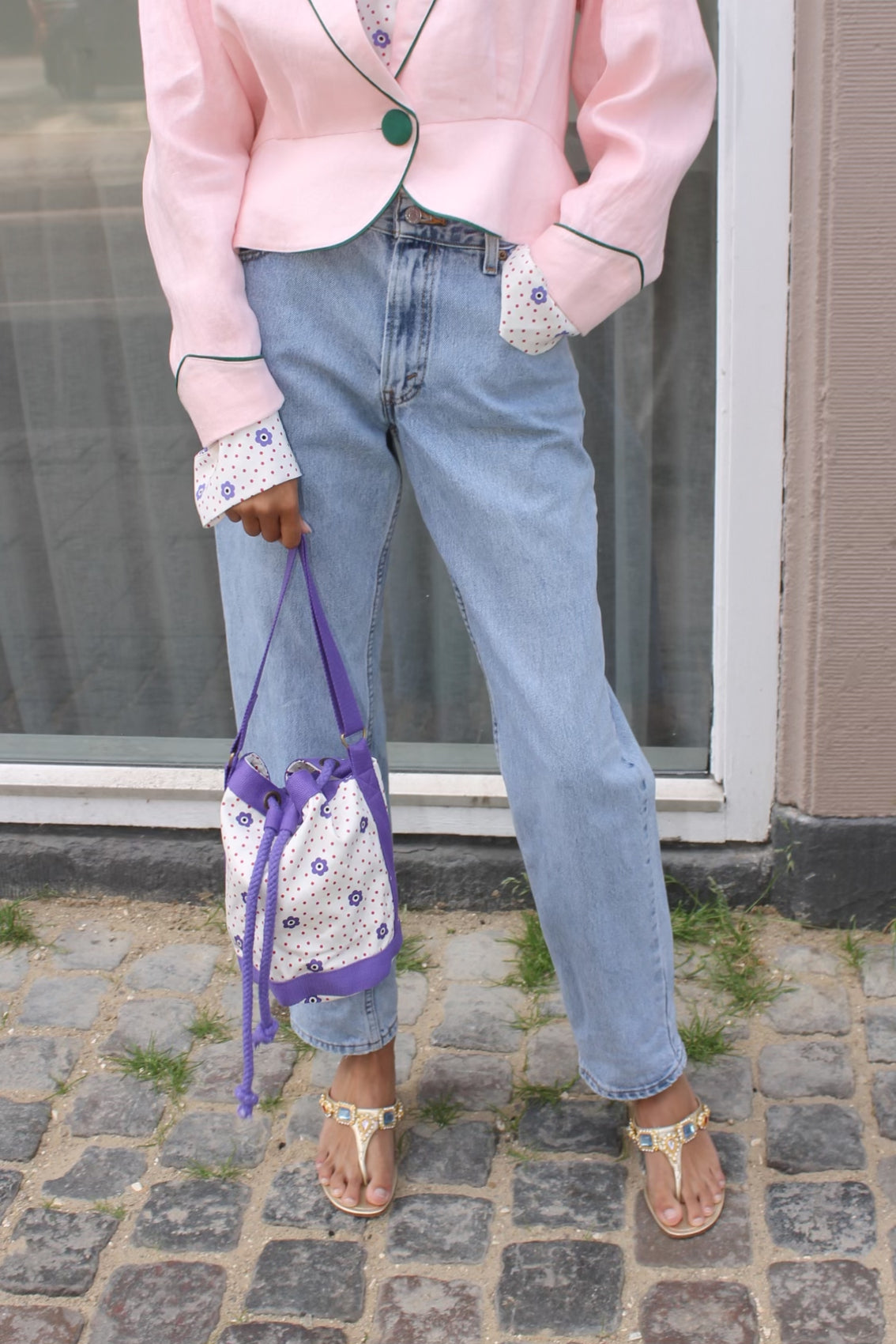 The Small Fern Bag in White Daisy cotton canvas with straps and strings in purple. Also available as Large Fern Bag - Navy Flower Canvas.