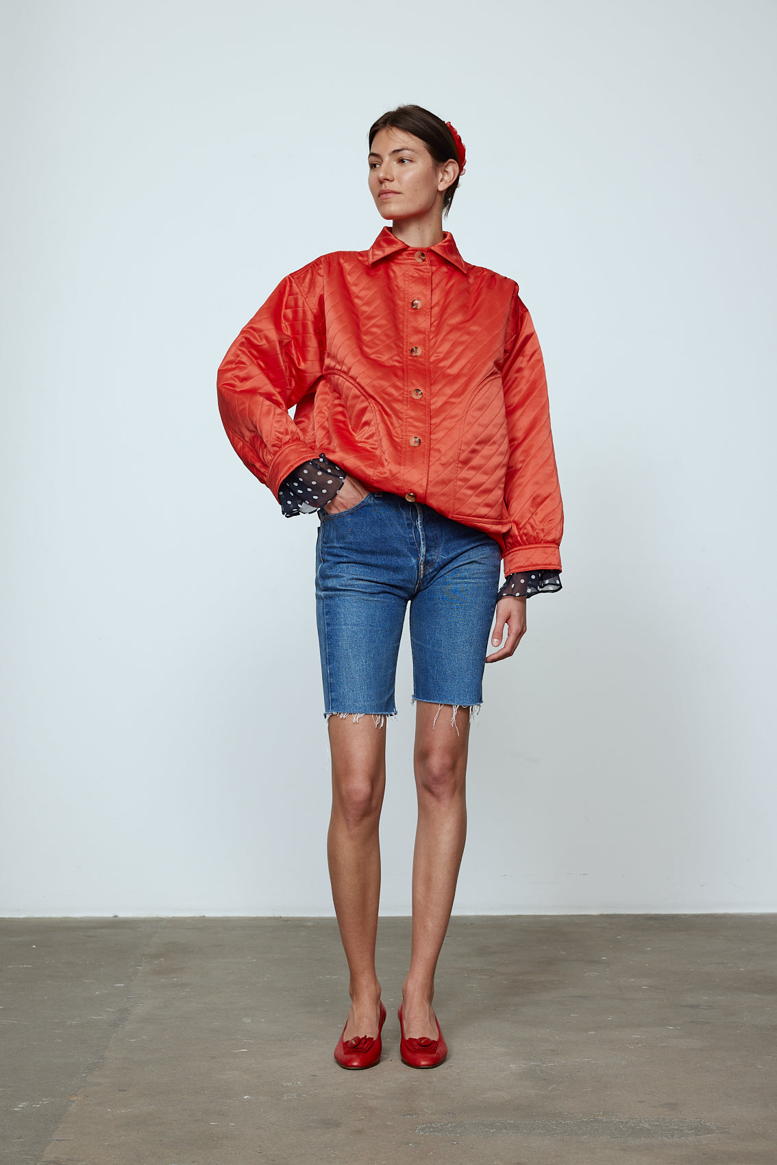 The Mimi Jacket in Orange Duchess. A new rounded shape inspired by the 80s in shiny quilted fabric with orange lining and big round buttons.  Style it over dresses, jeans, or shorts.   Material: 100% polyester. Lining: 100% viscose.