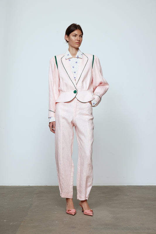 The Emma Pants in Baby Pink Linen. The pants feature cargo details on the side and large pockets with piping details in a contrasting color. Easily modify the shape of the pants with a button adjustment.  Style them with a t-shirt, blouse, or a matching Emma Jacket in Baby Pink Linen.   Also available in Orange and Navy.