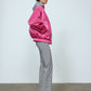 The Mimi Jacket in Hot Pink Duchess. A new rounded shape inspired by the 80s in shiny quilted fabric with orange lining and big round buttons.  Style it over dresses, jeans, or leggings.   Material: 100% polyester. Lining: 100 % viscose.