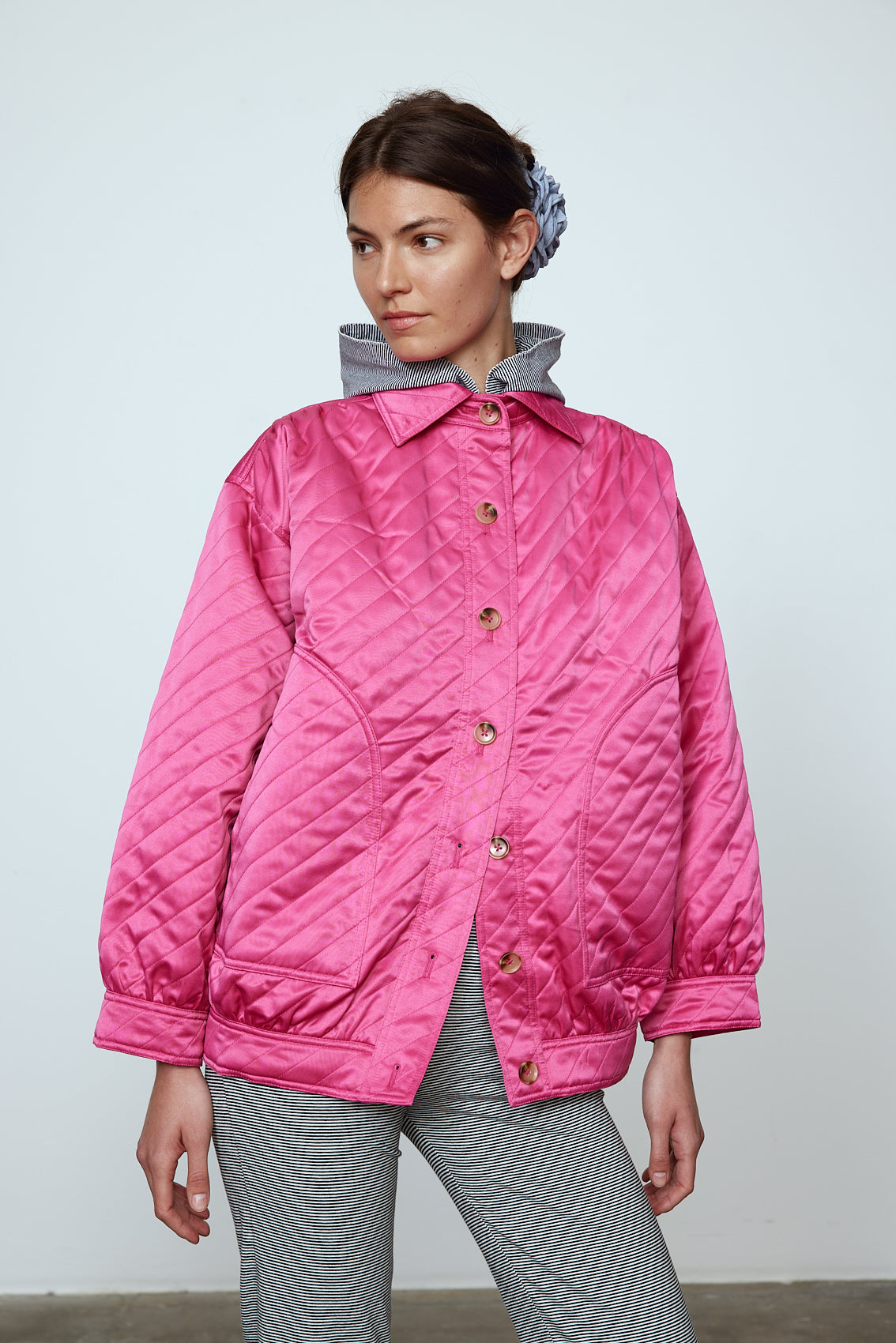 The Mimi Jacket in Hot Pink Duchess. A new rounded shape inspired by the 80s in shiny quilted fabric with orange lining and big round buttons.  Style it over dresses, jeans, or leggings.   Material: 100% polyester. Lining: 100 % viscose.