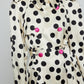 Caro Editions Roberta Coat features a black and white polka dot print on heavy cream-colored silk, with a matching belt and pink silk-covered buttons. Material: 100% Silk.