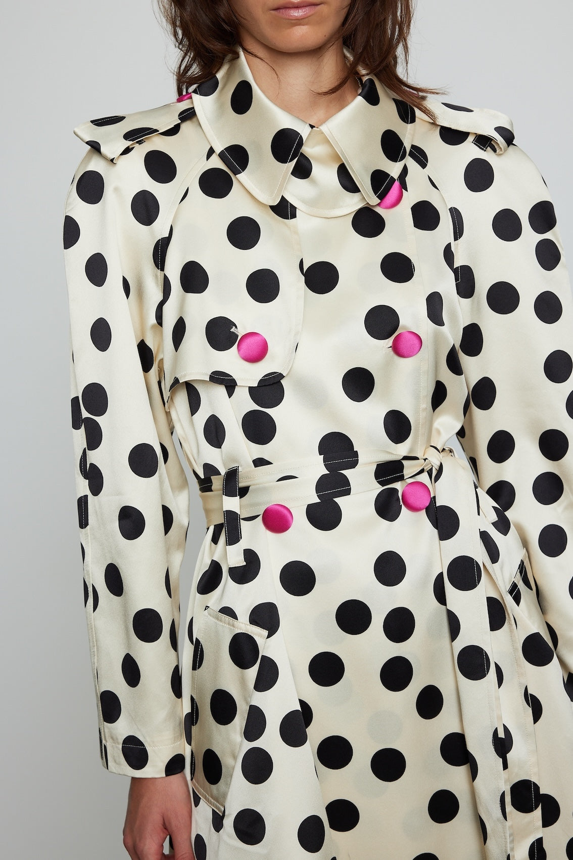 Caro Editions Roberta Coat features a black and white polka dot print on heavy cream-colored silk, with a matching belt and pink silk-covered buttons. Material: 100% Silk.