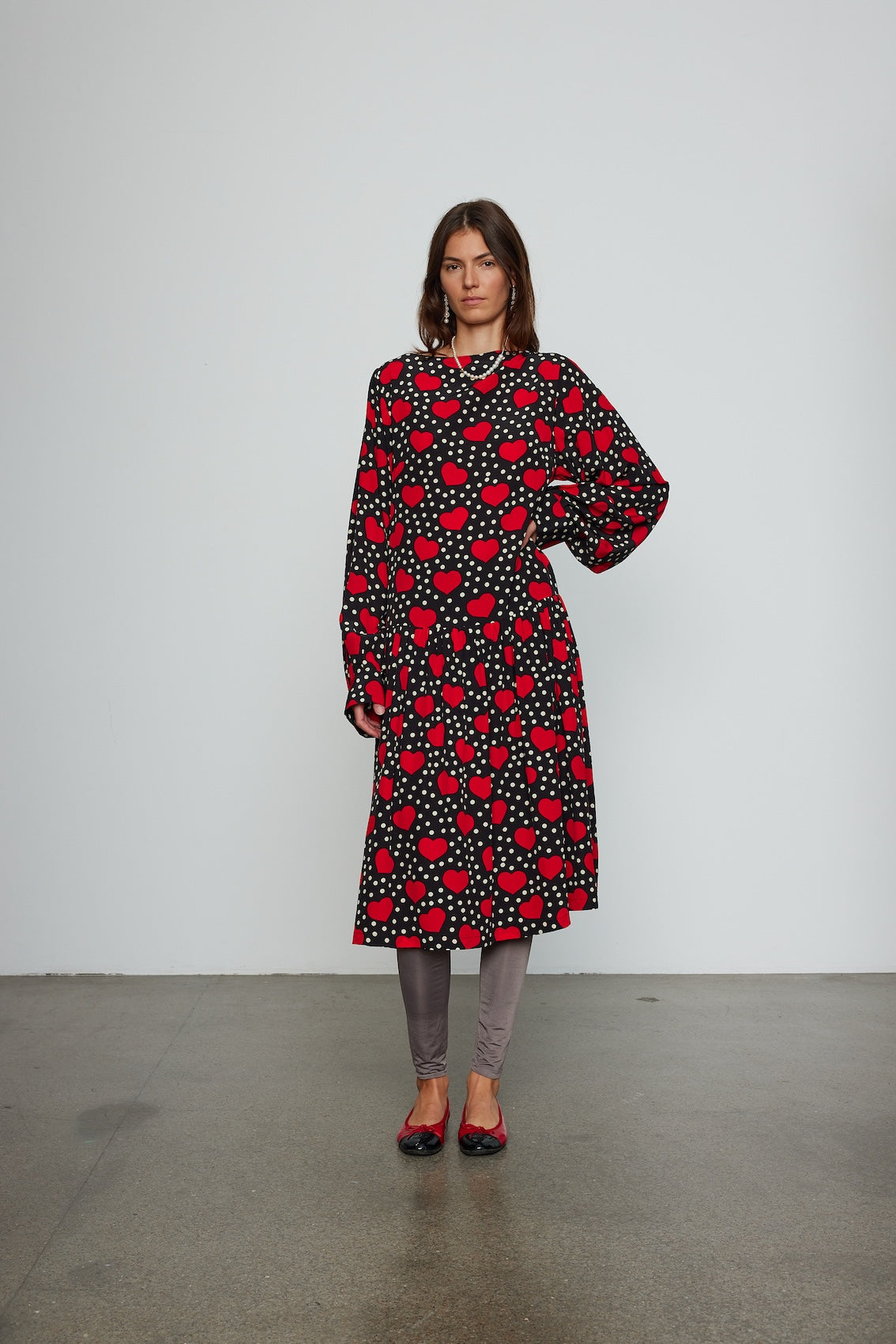 Caro Editions Holly Dress is an oversized style with a high neckline, low back with a large bow detail, and our long draped signature sleeves. The dress is made from soft silk crepe de chine featuring a heart print. Style it with an open shirt or denim jacket.