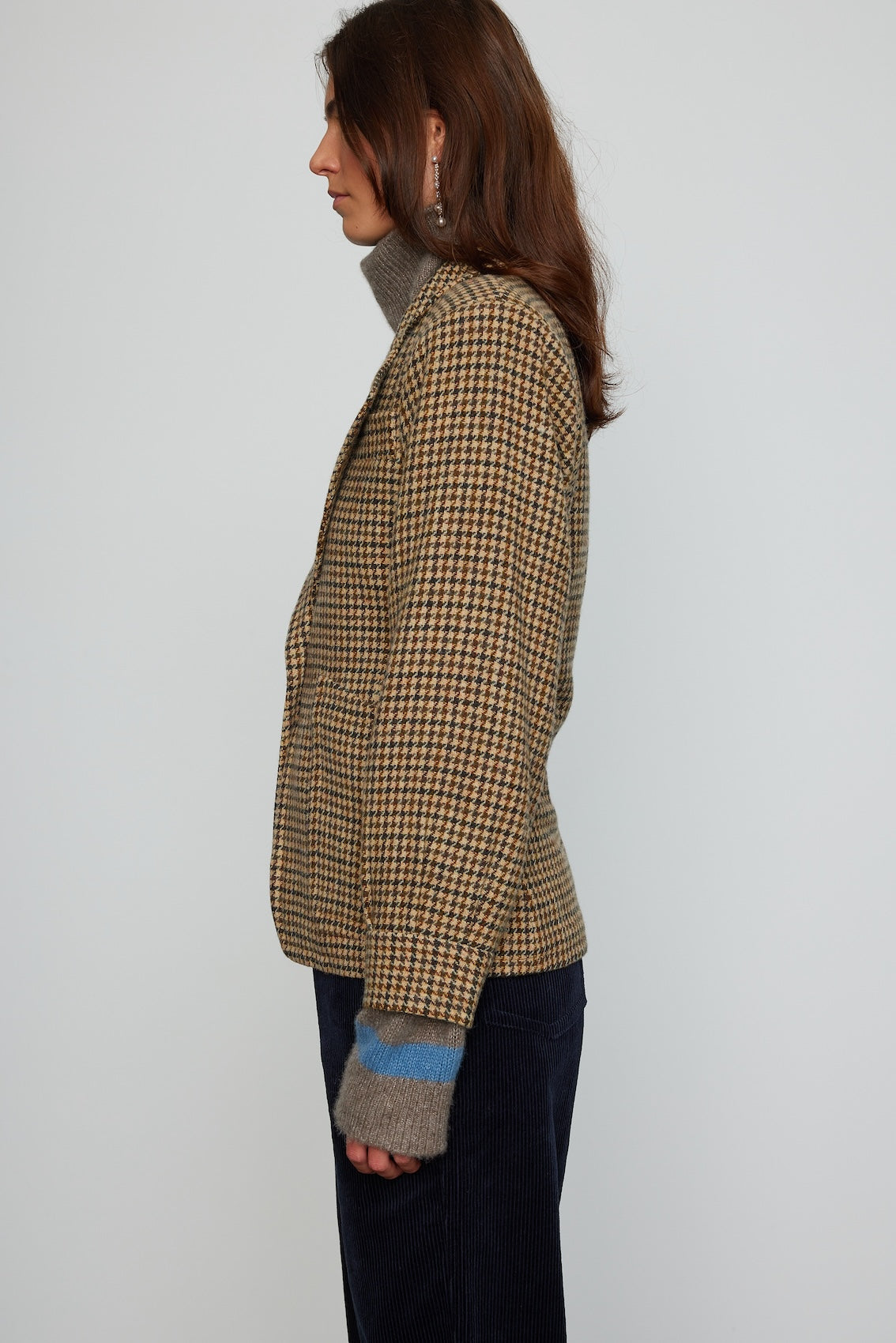 Caro Editions The Annika Jacket in a classic houndstooth tweed The jacket features a single-button closing at the front, wide padded shoulders, and large front pockets. The jacket is slightly fitted around the waist.  Material: 100% wool. Lining: 100% viscose.