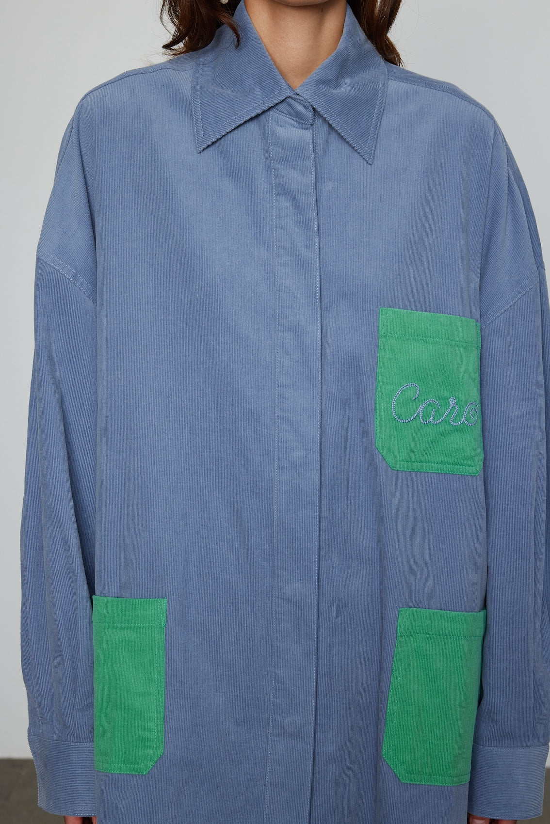 Caro Editions Frederik Shirt is an oversized cotton corduroy style with big sleeves, green pockets, and an embroidered Caro logo. Style it open over a dress, tank top, or t-shirt, or wear it buttoned-up.