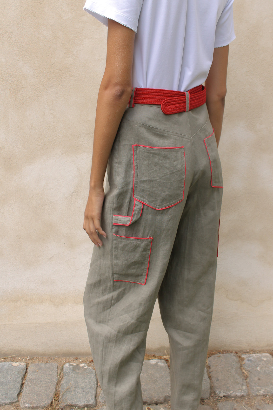 The Emma Pants in Khaki Linen. The pants feature cargo details on the side and large pockets with piping details in a contrasting color. Easily modify the shape of the pants with a button adjustment.  Style them with a t-shirt, blouse, or a matching Emma Jacket in Khaki.  Also available in Orange, Pink and Navy.  Material: 100% linen. Lining: 100% viscose.  The model is 175cm (5'9") and is wearing a size S.