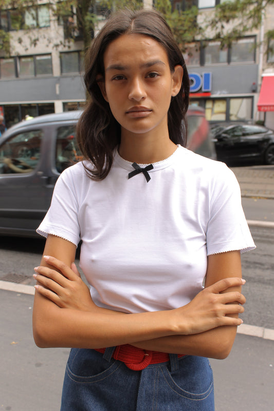 Caro Editions' new signature line in jersey cotton.  The Caro T-shirt is a fitted style with short sleeves, a ribbon bow detail at the front, and embroidered Caro Editions logo on the back.   Also available in Red White stripe, and Black White stripe.  Style the Caro T-shirt under shirts or dresses, or wear them on their own.  Material: 95% cotton, 5% elastane. Bow: 100% Polyester.  The model is 175cm (5'9") and is wearing a size S.